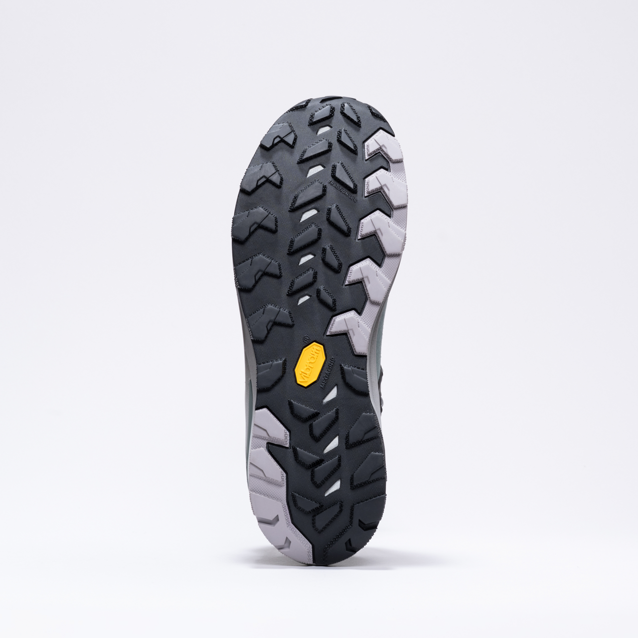Sole of a black and gray athletic shoe with rugged, multidirectional tread pattern.